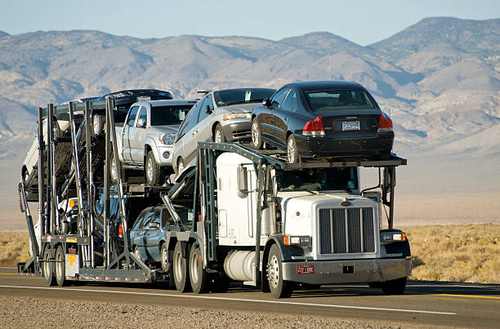 Open auto transport hauler navigating mountainous interstate terrain typical of North Georgia's foothills